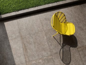 sedia gialla su pavimento esterno con grandi mattonelle in pietra naturale